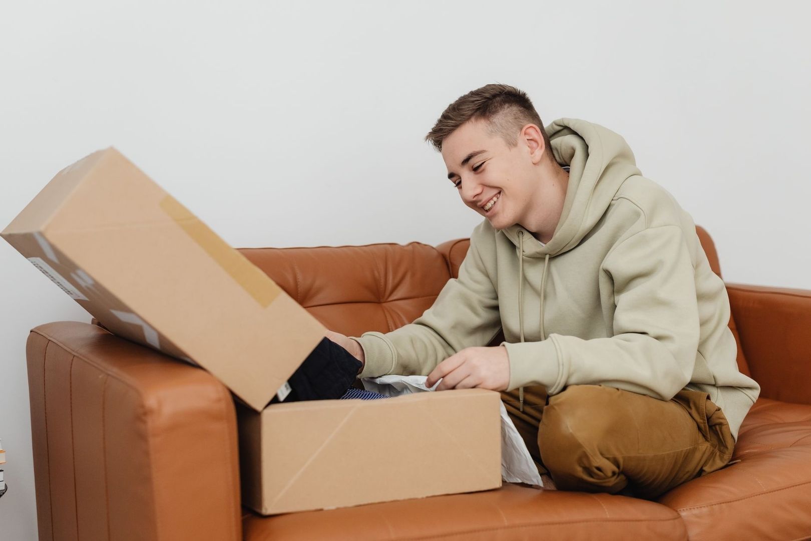Leende kund packar upp ett klädpaket på en skinnsoffa